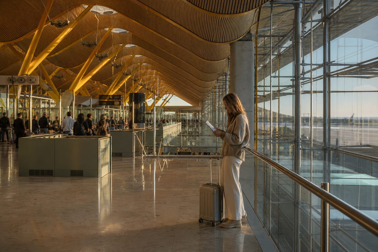 Viajera consultando su documentación junto a una maleta en una terminal europea